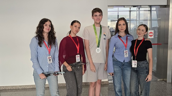 mai multi elevi fete si baieti cu medalii la gat pe un aeroport