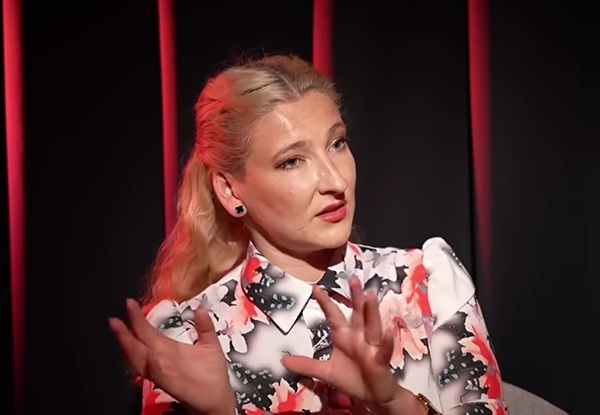 femeie blonda cu parul lung si bluza cu flori gesticuleaza
