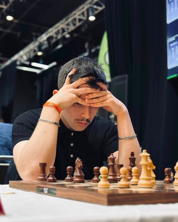 felix ilinca se uita pe tabla de sah imbracat in negru