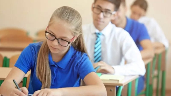 mai multi elevi baieti si fete sustin un examen in sala de clasa