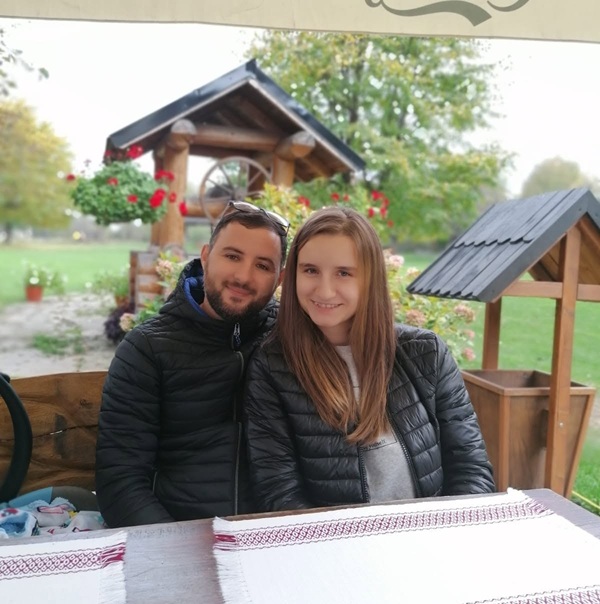 alexandra si gabriel ivanov stau in fata unei mese din lemn intr-un foisor afara in aer liber