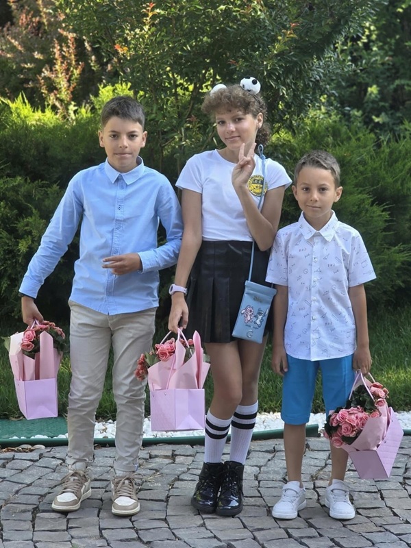 cei trei copii ai mirelei vaida imbracati de scoala cu pungi de cadouri si flori in mana