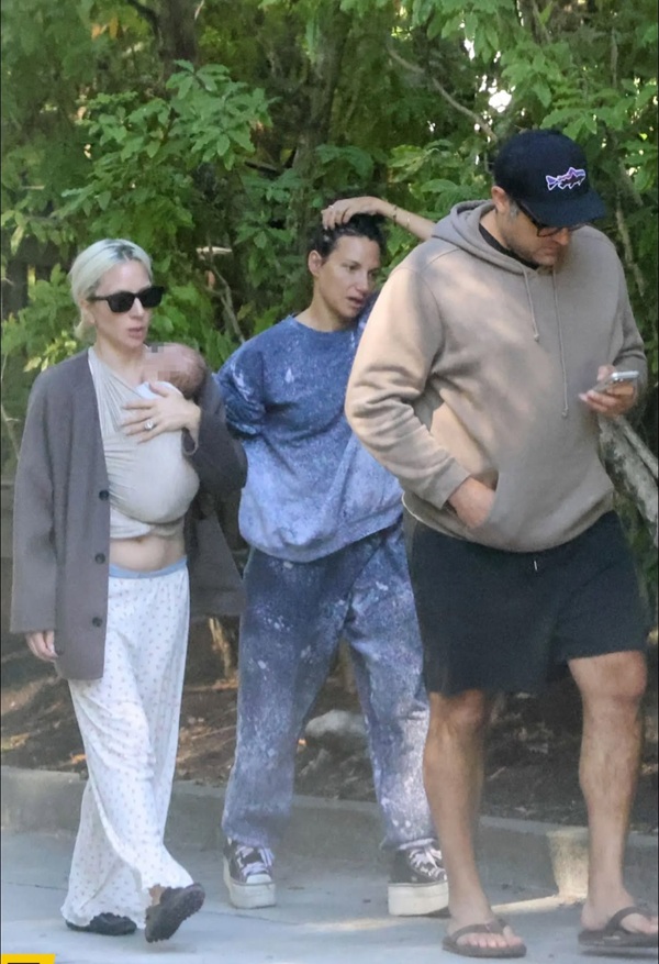 lady gaga alaturi de partenerul ei si de un apropiat la plimbare cu un bebelus in marsupiu