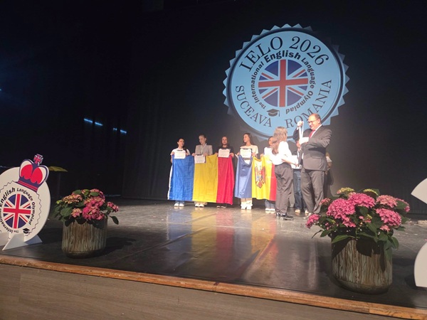 profesor inmaneaza premii pe scena elevilor