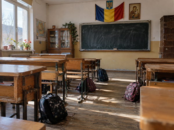 mai multe ghiozdane pe jos intr-o sala de clasa