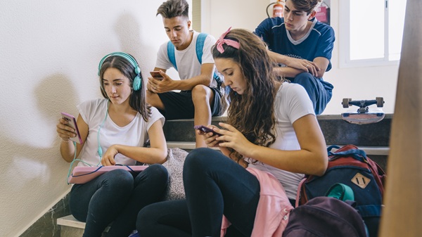mai multi adolescenti stau pe telefoane pe scari