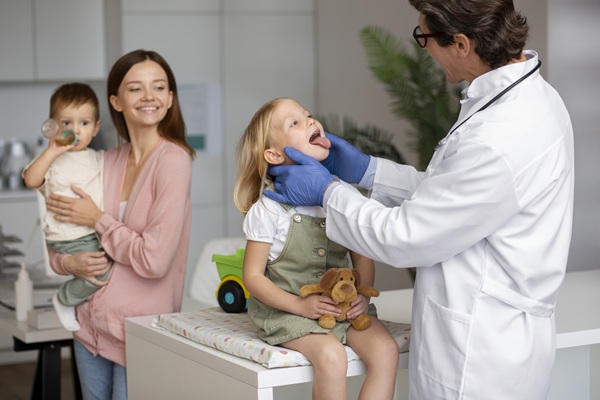 o mama isi tine copilul in brate in timp ce medicul consulta alt copil