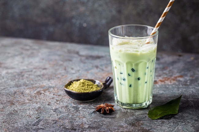 pe-o-masa-gri-este-un-pahar-cu-ceai-de-culoare-verde-cu-pai-si-bile-de-tapioca-iar-langa-este-un-castron-cu-pudra-de-matcha-si-o-frunza-verde