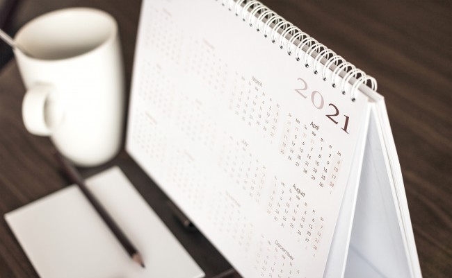 un-calendar-pentru-anul-2021-este-pe-o-masa-cu-o-cana-alba-alaturi-si-o-hartie-cu-un-pix