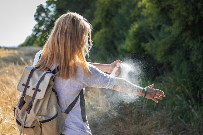 femeie-blonda-cu-rucsac-de-panza-isi-da-pe-maini-cu-un-spray-impotriva-tantarilor