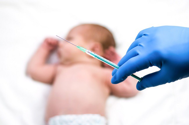bebelus-care-sta-pe-spate-si-o-seringa-cu-vaccin-in-ea
