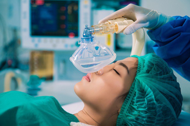femeie-asiatica-adormita-pe-masa-de-operatie-careia-i-se-pune-masca-de-oxigen