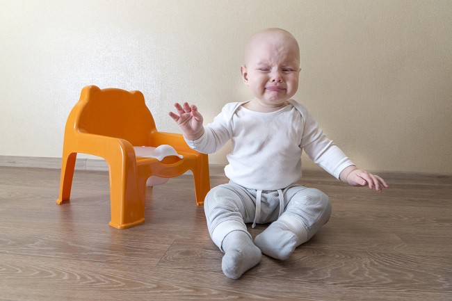 bebelus-care-sta-in-sezut-si-plange-si-care-are-o-olita-cu-scaunel-langa-el