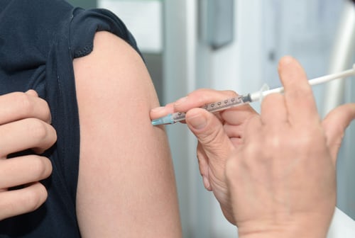 medic-care-vaccineaza-o-femeie-ce-isi-tine-maneca-tricoului-negru-cu-mana