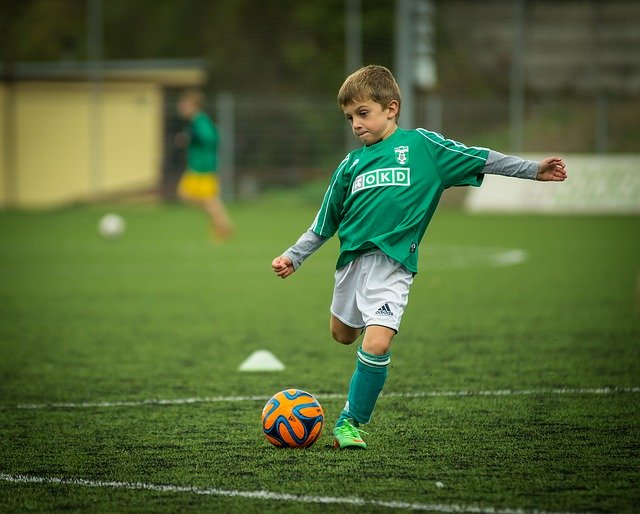 Baiat in tricou verde care joaca fotbal