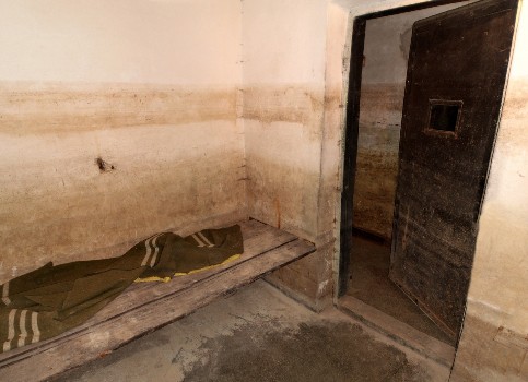 fortul-13-jilava-interior-al-unei-celule-pentru-detinuti-in-care-se-afla-un-pat-cu-o-patura-verde-cu-dungi-albe