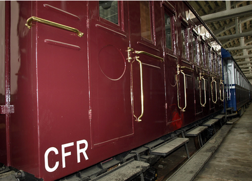 trenul-regal-poza-din-exterior-cu-un-vagon-rosu-inchis-iar-in-fata-lui-este-unul-albastru