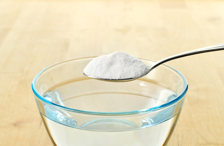 Bicarbonat de sodiu in lingurita deasupra unui pahar cu apa