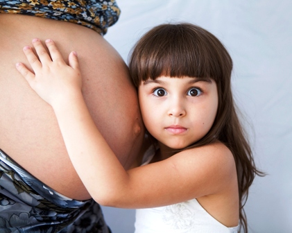 Poza burta de femeie gravida si fetita lipita de burta lui mami